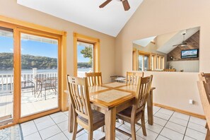A dining area with a table and chairs, large windows with a view of the water, and a ceiling fan. - Casa Del Sol - Three Bedroom House, Sleeps 10 (Rocky Mount)