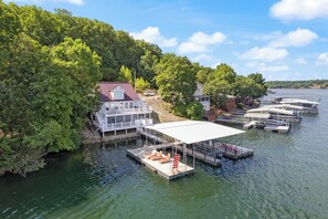 A lakeside house with a dock, boats, and a covered area with lounge chairs. - Casa Del Sol - Three Bedroom House, Sleeps 10 (Rocky Mount)