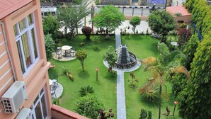Un patio con una fuente central, rodeado de follaje y una zona de estar.