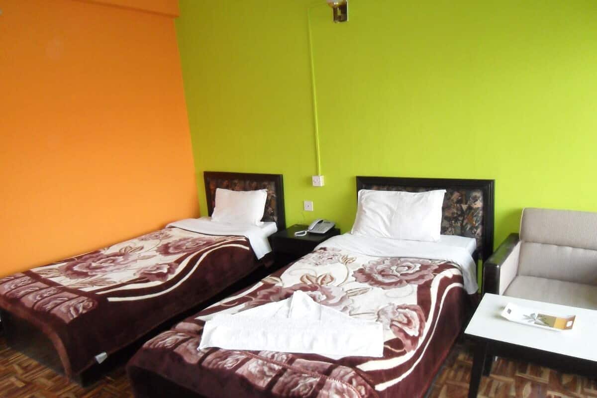Una habitación de hotel con dos camas, una mesita pequeña y una silla.