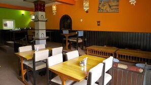 Un restaurante con mesas y sillas de madera, una pared verde y un mural.
