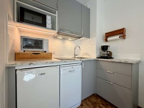 A compact kitchen with a microwave, a coffee maker, and a dishwasher.
