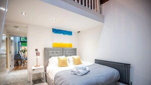 Un dormitorio moderno con una cama grande, una mesita de noche, un radiador y vistas al exterior.