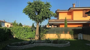 A residential property with a well-maintained garden, a large tree, and a house with a tiled roof. - Ca' Le Rose (Bagnolo San Vito)