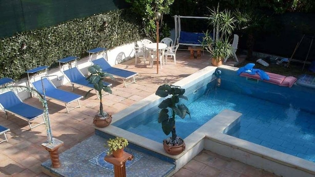 A swimming pool with lounge chairs and potted plants. - Ca' Le Rose (Bagnolo San Vito)