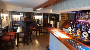 Un espace bar avec des meubles en bois, un comptoir où sont exposées différentes bouteilles et un menu écrit à la craie.