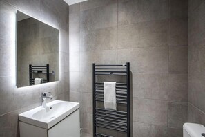 A modern bathroom with a white sink, a mirror, and a towel rack.