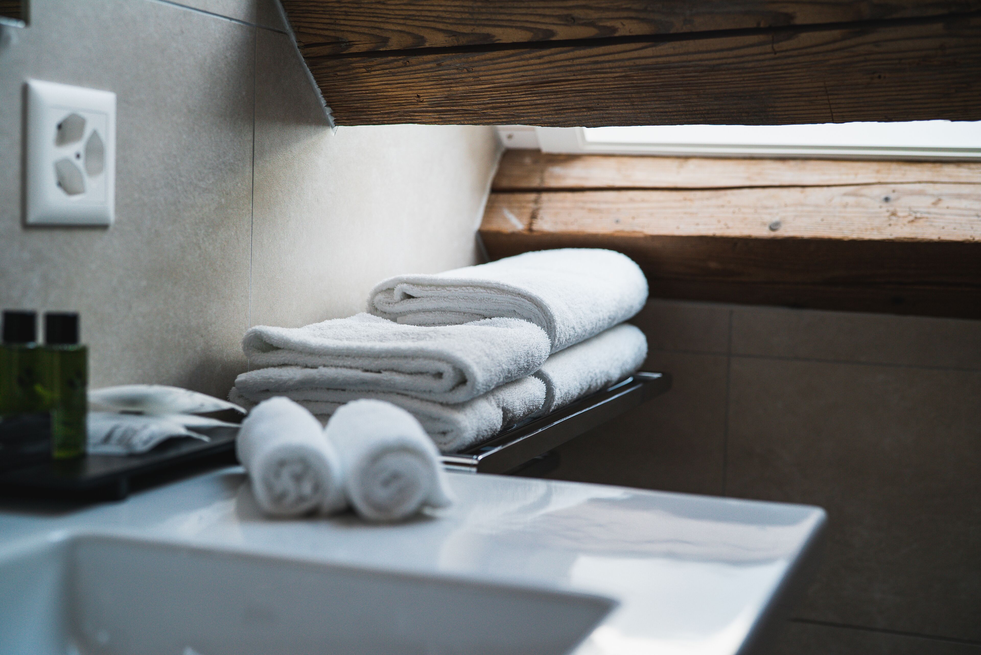 Une salle de bain avec un rebord de fenêtre en bois, un porte-serviettes avec des serviettes pliées et un lavabo blanc.