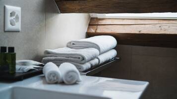 Une salle de bain avec un rebord de fenêtre en bois, un porte-serviettes avec des serviettes pliées et un lavabo blanc.