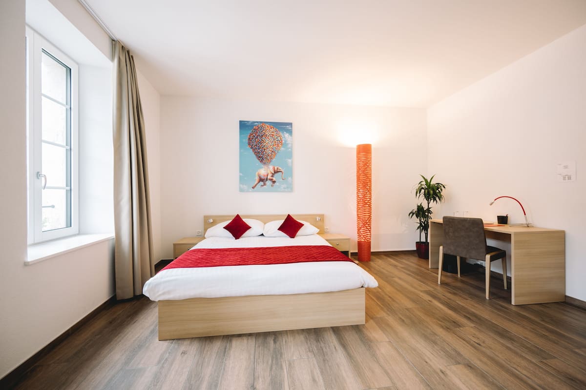 Een moderne hotelkamer met een houten bed, een bureau en een stoel.