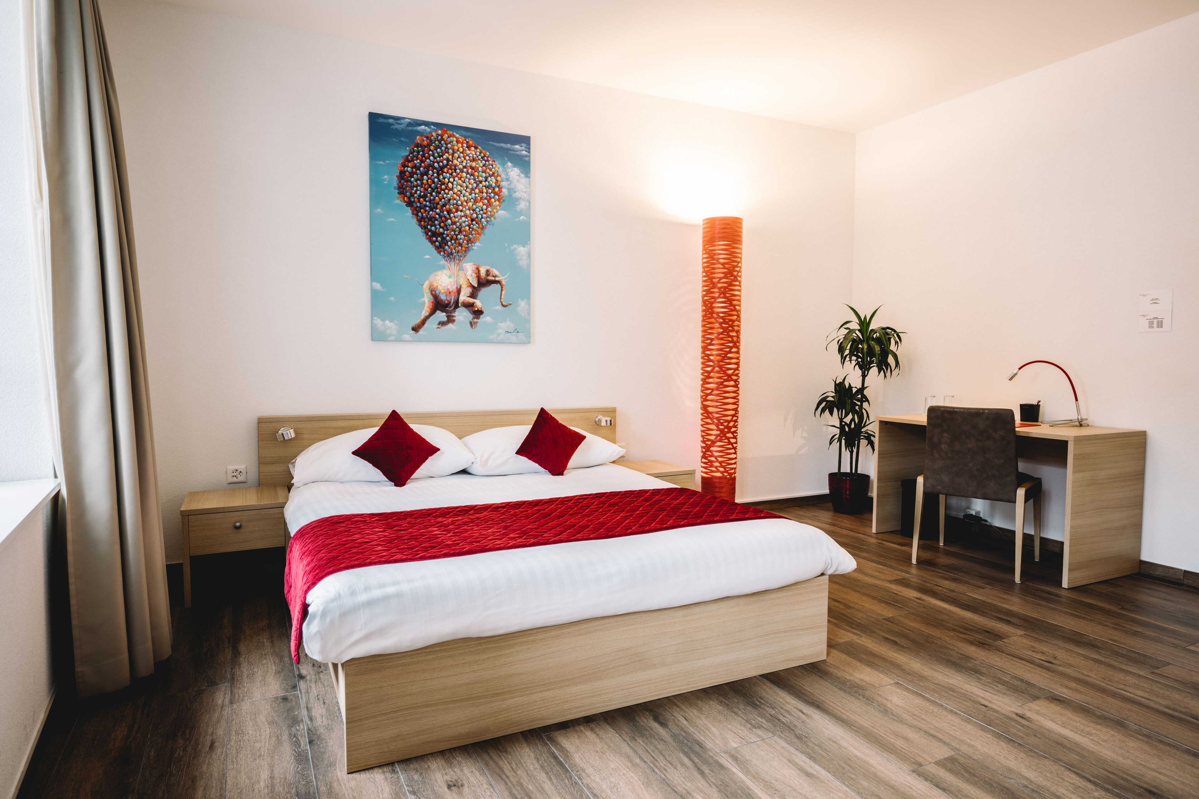 A modern hotel room with a wooden bed, a desk, and a chair.