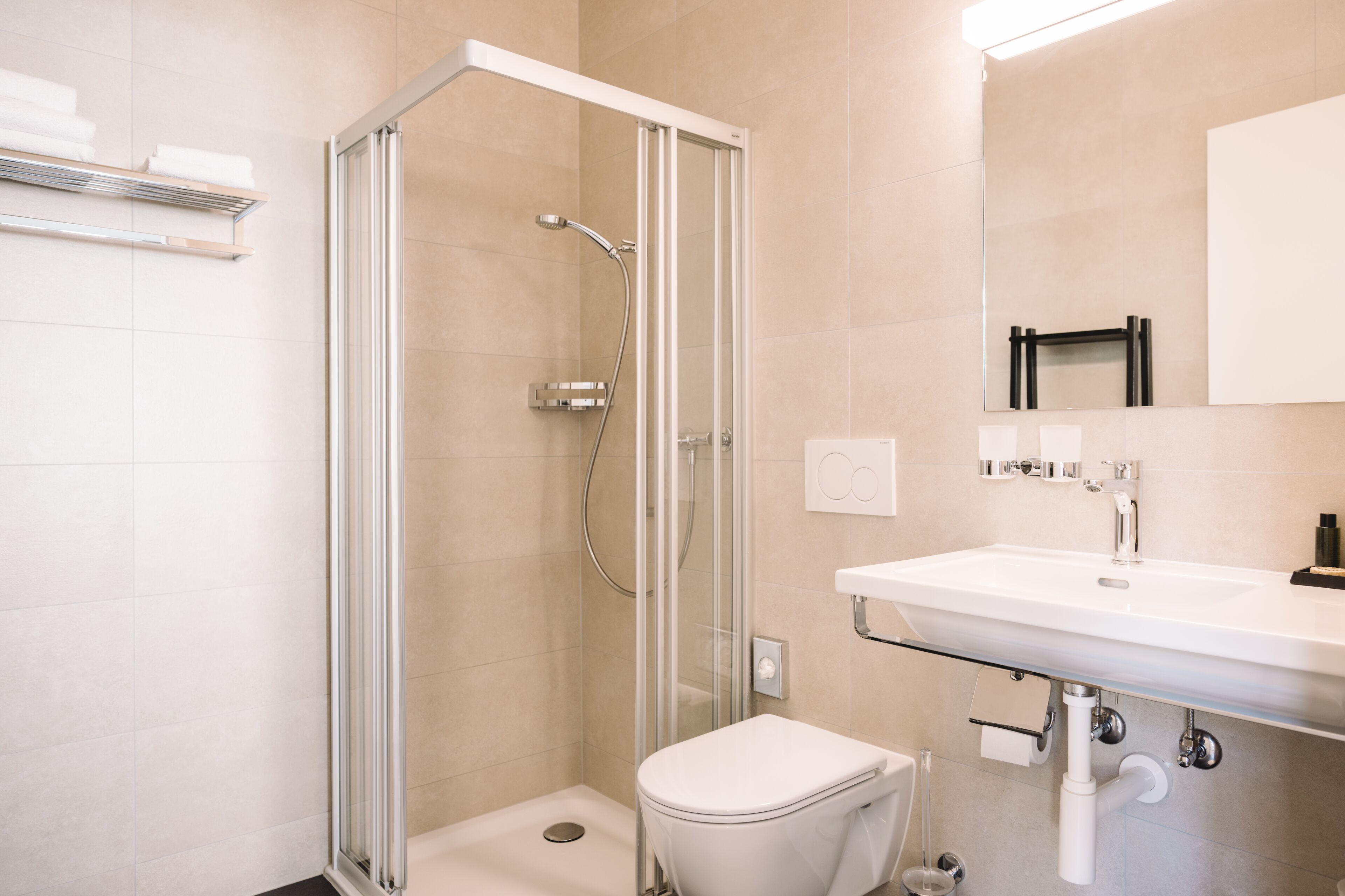 Un baño moderno con cabina de ducha de vidrio, un lavamanos blanco y un inodoro.