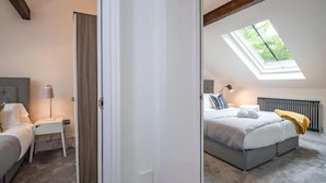 A bedroom with a skylight, a bed with pillows, a bedside table with a lamp, and a chair. - The Wolsey at 52 Old Elvet (Durham)
