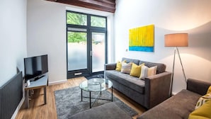 A modern living room with a sofa, coffee table, and TV. - The Wolsey at 52 Old Elvet (Durham)