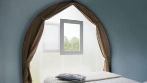 A bedroom with a window, a bed, and a view of greenery outside.