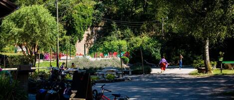 A campsite with a red bicycle, a sign for 'Pelforth Camping Les Bouleaux', and a dirt path.