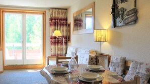 A dining area with a table set for four, a lamp, and a view of the outdoors through a sliding door.