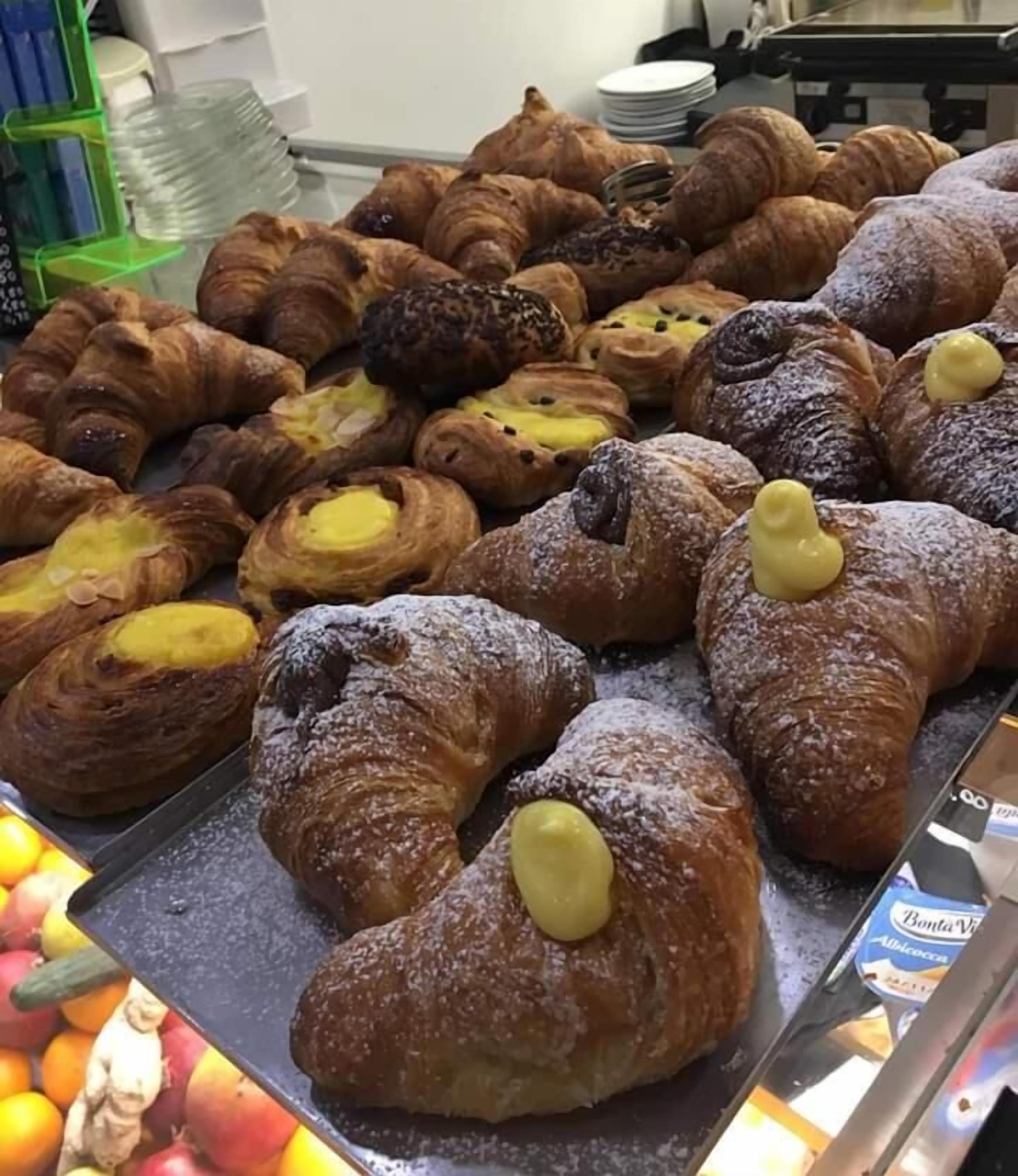 A display of assorted pastries including croissants and danishes, some topped with yellow cream.