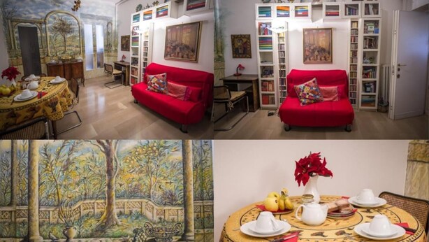 A dining area with a round table set for a meal, a red sofa, and a bookshelf filled with books and decorative items. - Il Leoncino (Rome)