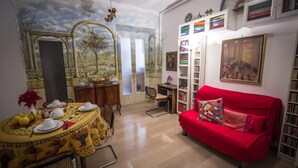 A dining area with a mural, a red sofa, and a bookshelf. - Il Leoncino (Rome)