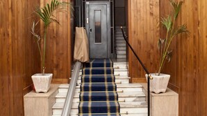 A wooden hallway with a blue carpet leading to a door. - Il Leoncino (Rome)