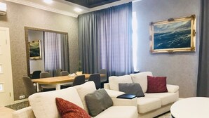 A modern living room with a beige sofa set, a round coffee table, and a dining area with a wooden table and chairs. - Kreschatik Str two bedroom VIP (Shevchenkivs'kyi district)
