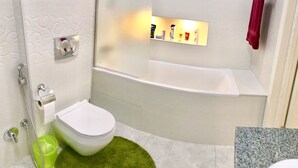 A bathroom with a toilet, shower, and bathtub. There is a green rug on the floor. - Kreschatik Str two bedroom VIP (Shevchenkivs'kyi district)