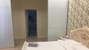 A bedroom with a bed, a nightstand, a dresser, and a door leading to another room. - Kreschatik Str two bedroom VIP (Shevchenkivs'kyi district)