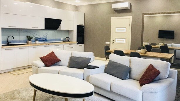 A modern living room with a sofa, a coffee table, and a dining area with a table and chairs. - Kreschatik Str two bedroom VIP (Shevchenkivs'kyi district)
