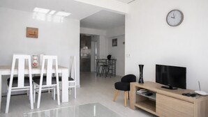 Un espacio moderno para vivir con comedor, televisor y un reloj en la pared.