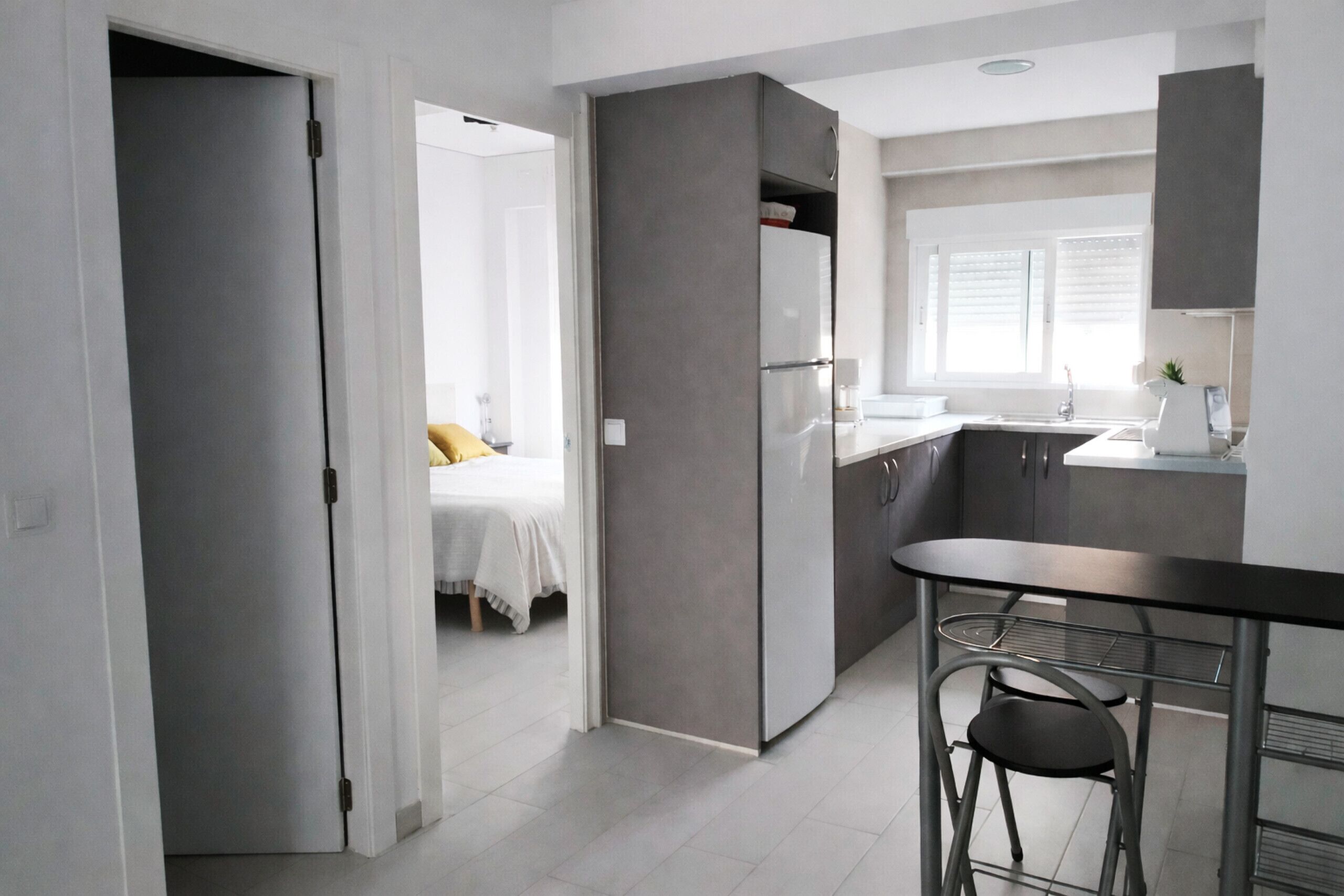 Eine moderne Küche mit Kühlschrank, Spüle und Barhocker.