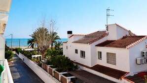 Zona residencial costera con un edificio blanco que tiene techo de tejas, un balcón y vistas al mar.