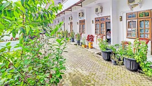 Een binnentuin met plantenpotten, een betegeld pad en traditionele houten deuren.