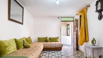 A room with a bed, a sofa, a small table, and a mirror.