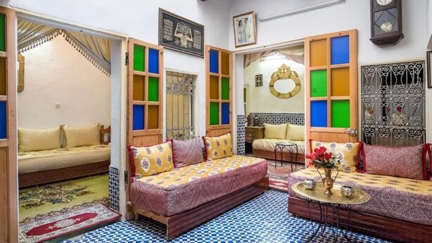 A cozy room with a bed, a sofa, and a small table with a vase of flowers. - Dar Fatimazahra (Fes)