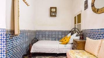 Una habitación con una cama, una mesita y un reloj de pared.