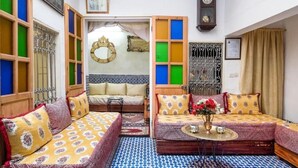 A cozy living room with a sofa set, a small table with a vase, and a decorative mirror. - Dar Fatimazahra (Fes)