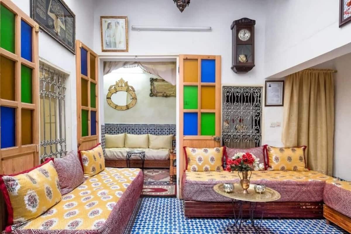 Un salon chaleureux avec un ensemble de canapés, une petite table surmontée d’un vase et un miroir décoratif.