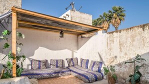 A rooftop terrace with a wooden pergola, a patterned sofa, and potted plants. - Dar Fatimazahra (Fes)