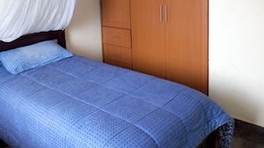 Un dormitorio con una cama, un armario de madera y un dosel blanco.