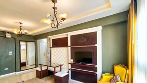 A living room with a TV, a yellow armchair, a glass coffee table, and a chandelier. -  Beautiful sea view Apt,in the heart of Alexandria (alexandria)