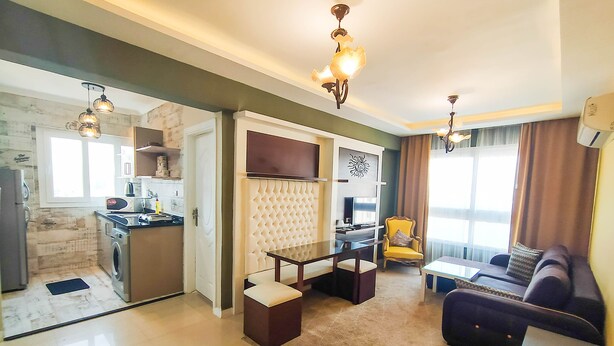 A modern apartment with a kitchen, dining area, and living room. It includes a sofa, a dining table, and a TV. -  Beautiful sea view Apt,in the heart of Alexandria (alexandria)