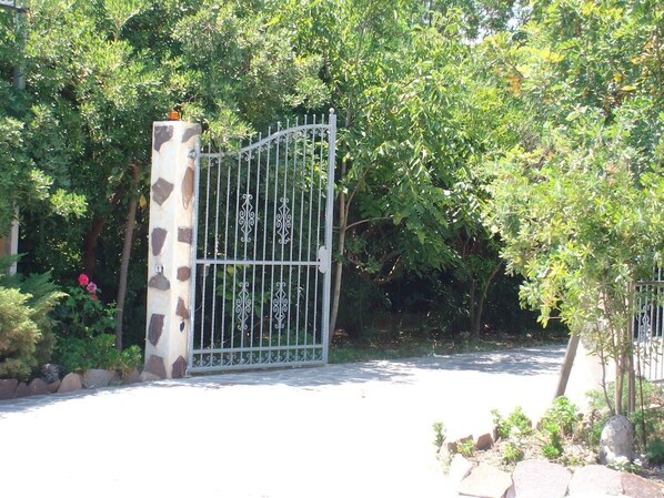 Una entrada protegida con un pilar de piedra y una reja metálica.