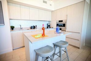 Cozinha moderna com ilha central, dois banquetes e eletrodomésticos embutidos.
