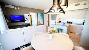 A modern living room with a white sofa, a round table, and a TV mounted on the wall.