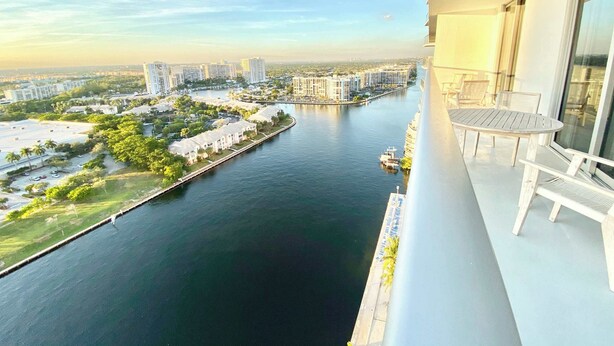 A balcony with a view of a river, buildings, and a boat.