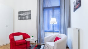 A room with two chairs, one red and one white, a small table with a plant, and a radiator. - Akacfa 18 Apartment (Budapest)