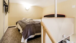 A bedroom with a bed, a desk, a chair, and a wall-mounted TV. - Akacfa 57 Apartment II. (Budapest)