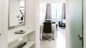 A hallway with a mirror, shelves, and a door leading to a room with a bed and a window. - Andrassy 1 Apartment (Budapest)