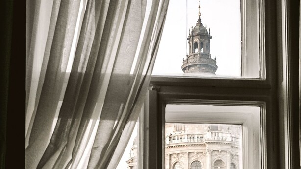 A window with a view of a historic building, a chair, and a lamp inside. - Andrassy 1 Apartment (Budapest)